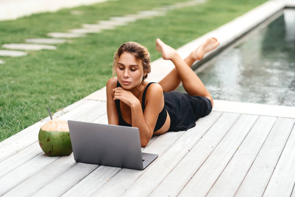 Mujer freelance escribiendo en el ordenador portátil con coco fresco . - Foto, imagen