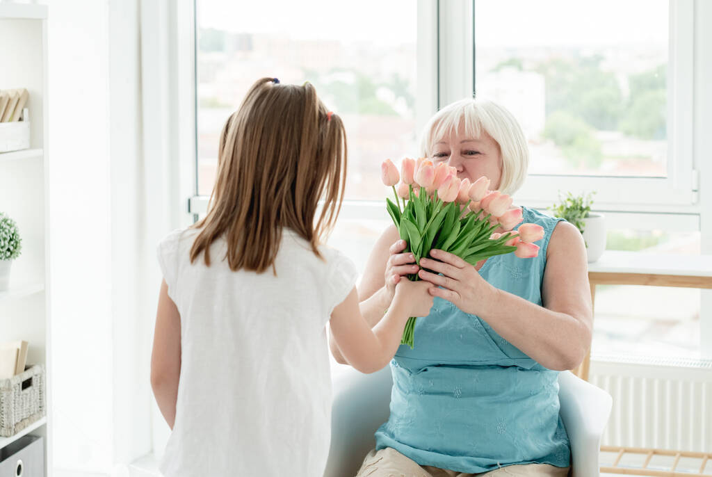 Niña dando flores a la mujer mayor - Foto, imagen