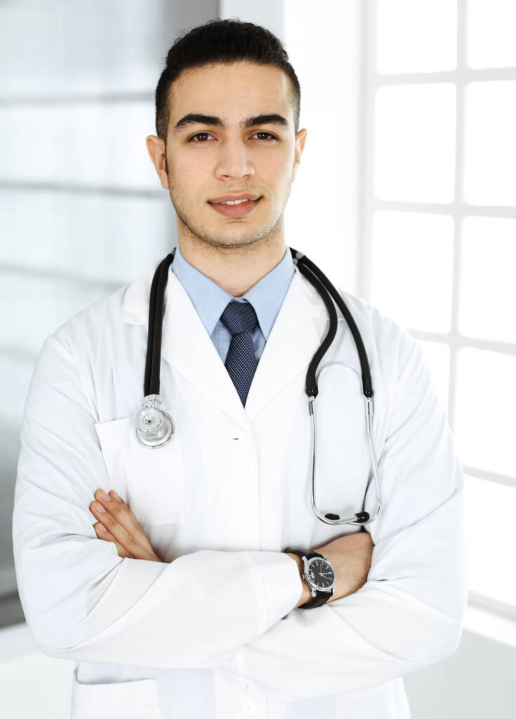 Arab doctor man is standing with crossed arms in clinic. Medicine and healthcare concept - Photo, Image