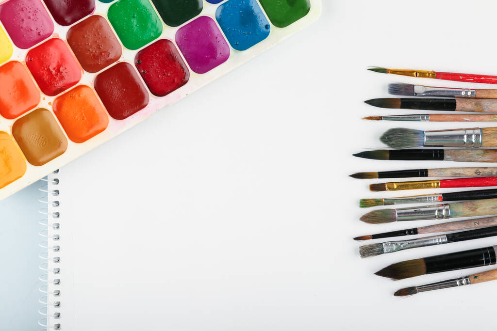 paint brushes, paints and paper are on the table, top view - Photo, Image