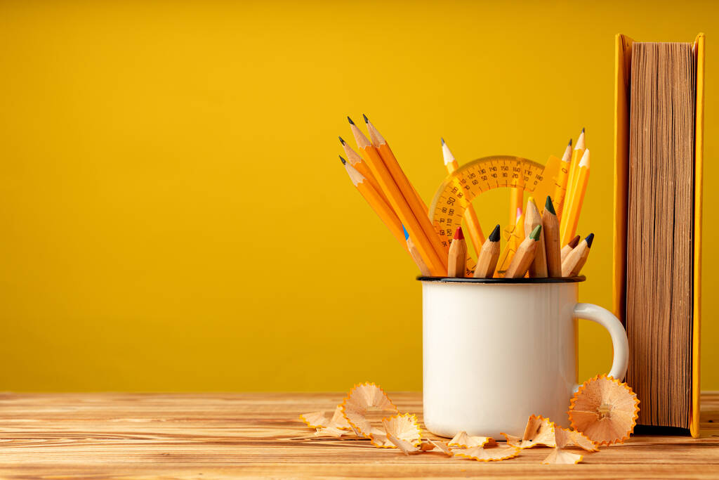 Металева чашка з гострими олівцями та стружками олівців на дерев'яному столі
 - Фото, зображення