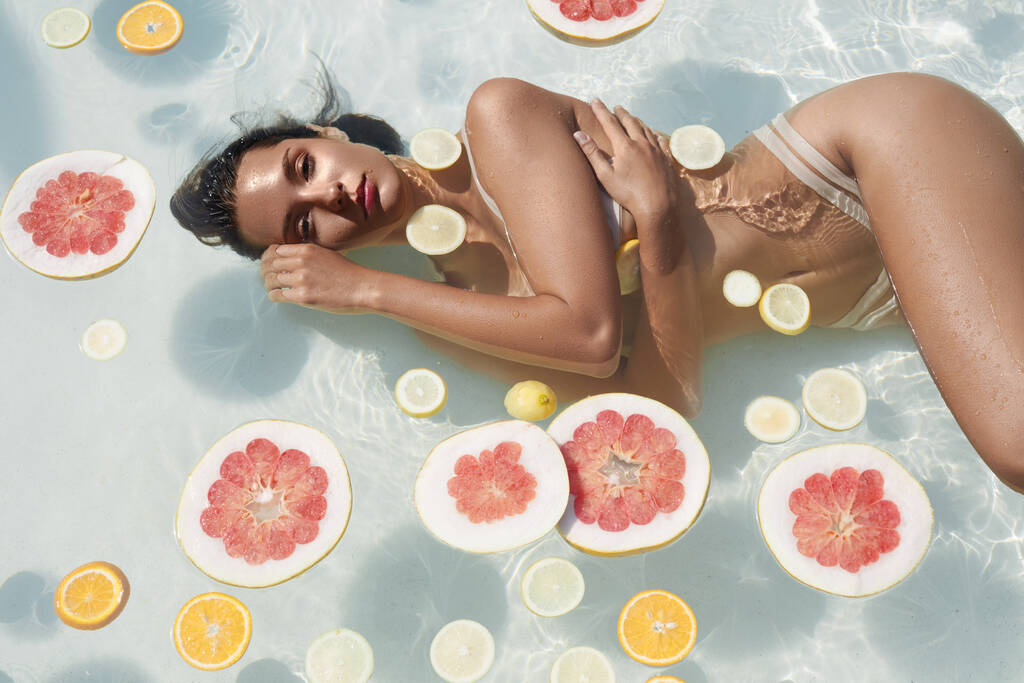 Beau portrait de filles dans la piscine avec des agrumes. Femme en bikini profitant d'une journée ensoleillée au SPA Resort. - Photo, image