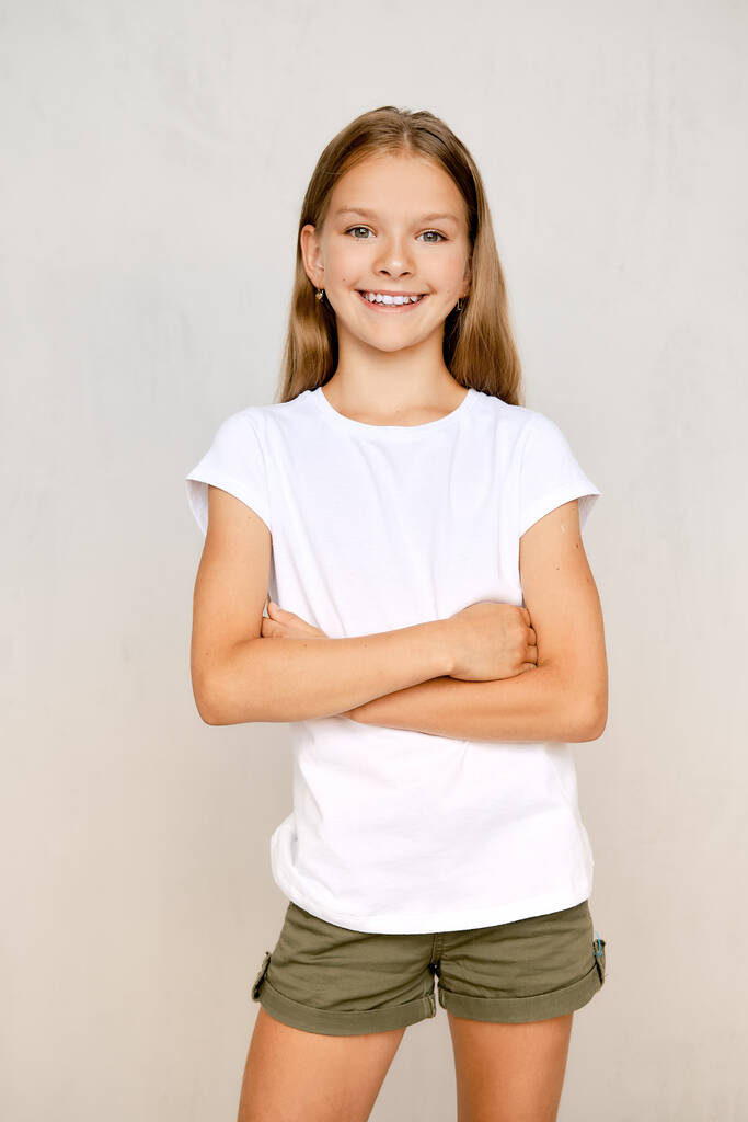 Portrait d'adolescente positive debout droite avec les mains croisées sur la poitrine - Photo, image