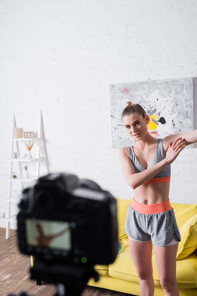 自宅でデジタルカメラの近くのスポーツ女性のトレーニングの選択的な焦点  - 写真・画像
