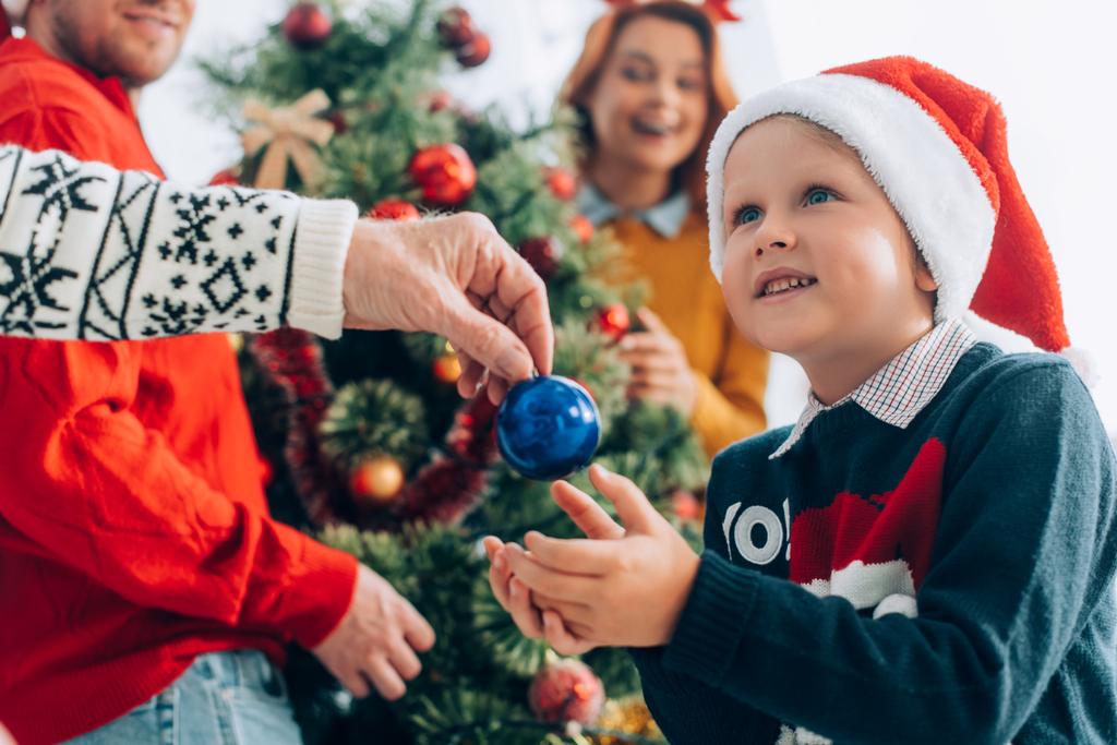 驚くべき孫にクリスマスボールを与える祖父の選択的な焦点 - 写真・画像