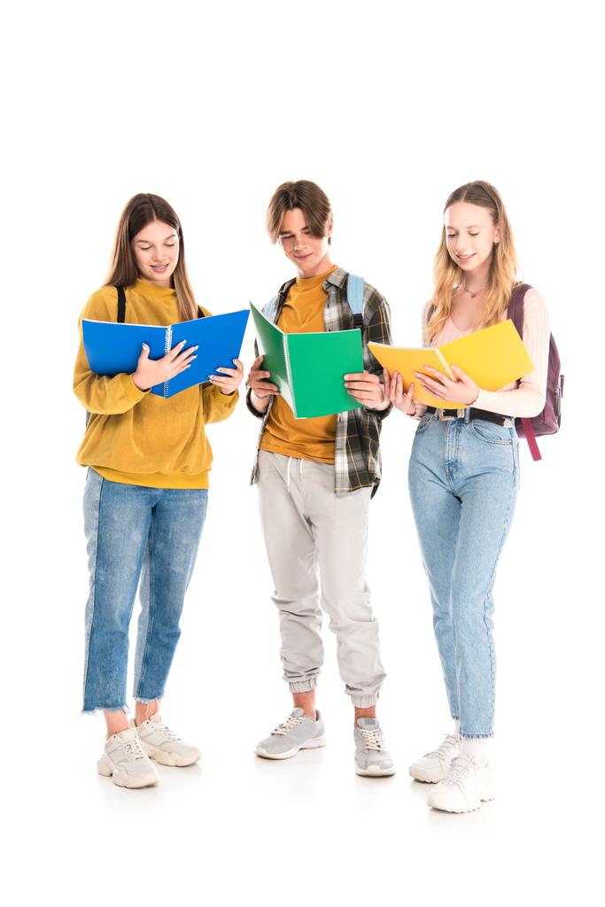 Lächelnde Teenager mit Rucksäcken betrachten Kopierbücher auf weißem Hintergrund - Foto, Bild