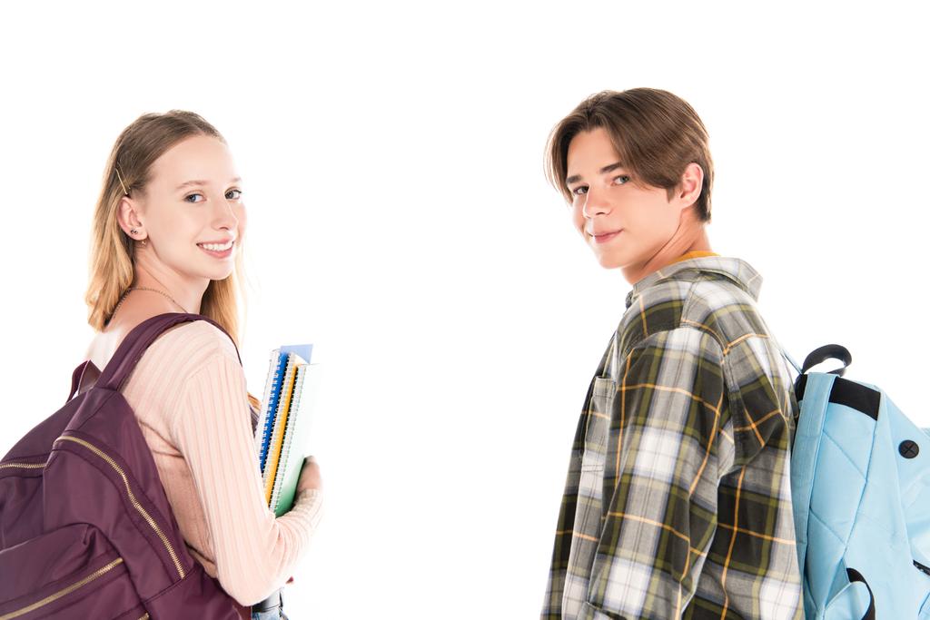 Teen friends smiling at camera while holding backpacks and notebooks isolated on white - Photo, Image