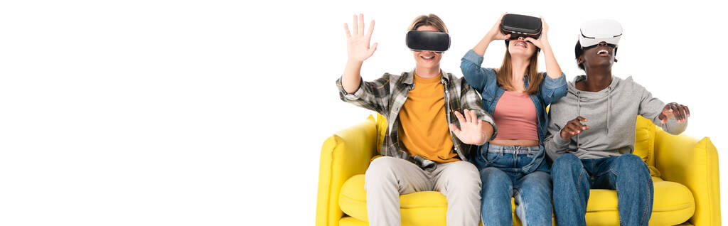 Horizontal crop of positive multiethnic teenagers using vr headsets on sofa isolated on white - Photo, Image
