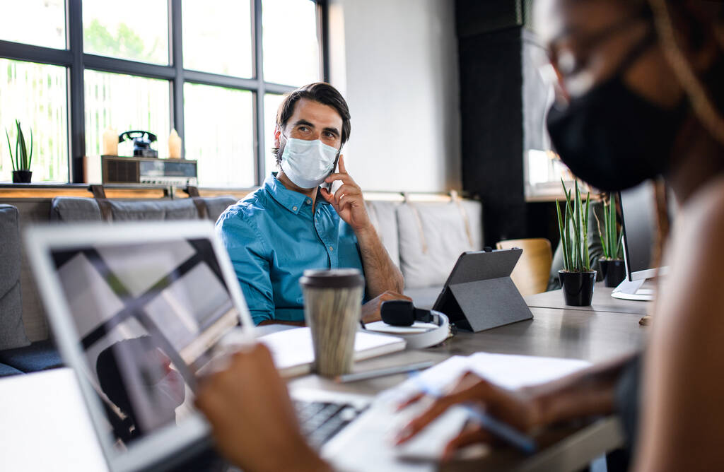 Деловые люди в масках в помещении офиса, возвращаются к работе после блокировки коронавируса. - Фото, изображение