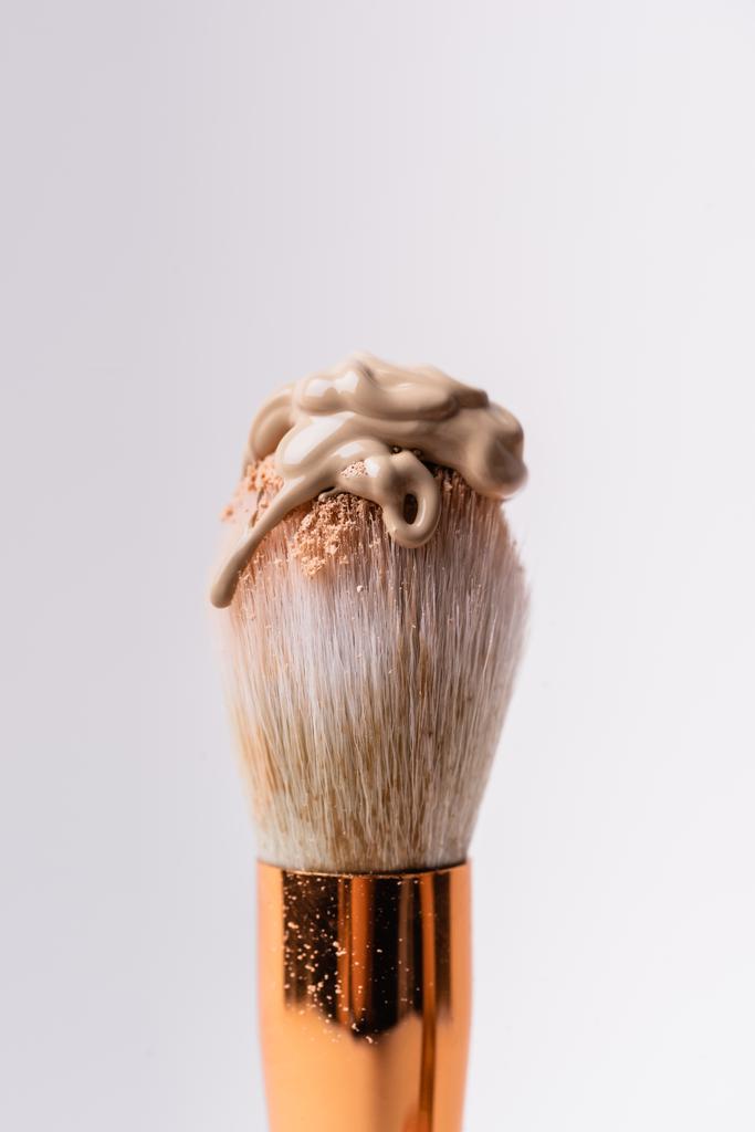 vista de cerca del cepillo cosmético con polvo facial y base aislada en blanco - Foto, imagen