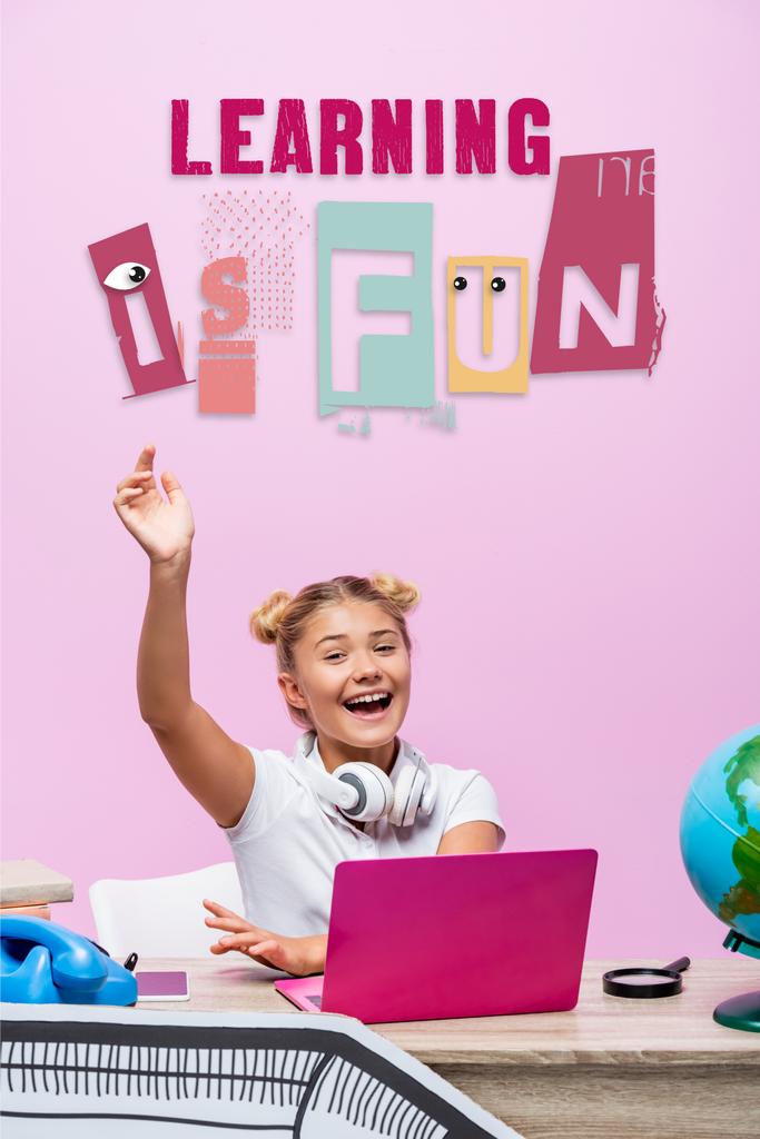 Школьница, сидящая с поднятой рукой рядом с ноутбуком, телефоном, учится весело, а бумажное искусство на розовом  - Фото, изображение