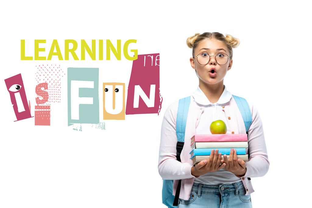 Sorprendido colegiala sosteniendo manzana y libros cerca de aprender es divertido letras en blanco  - Foto, imagen