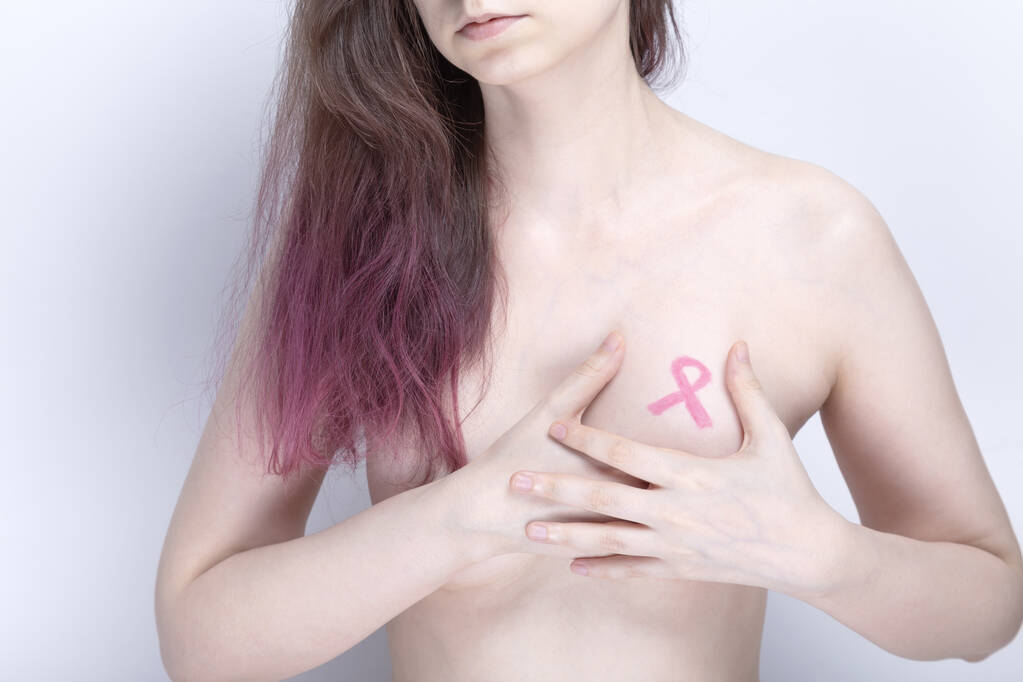 World Breast cancer day concept (en inglés). La mujer cubre su pecho con sus manos con cinta rosa pintada. Octubre Mes de concientización sobre el cáncer de mama - Foto, Imagen