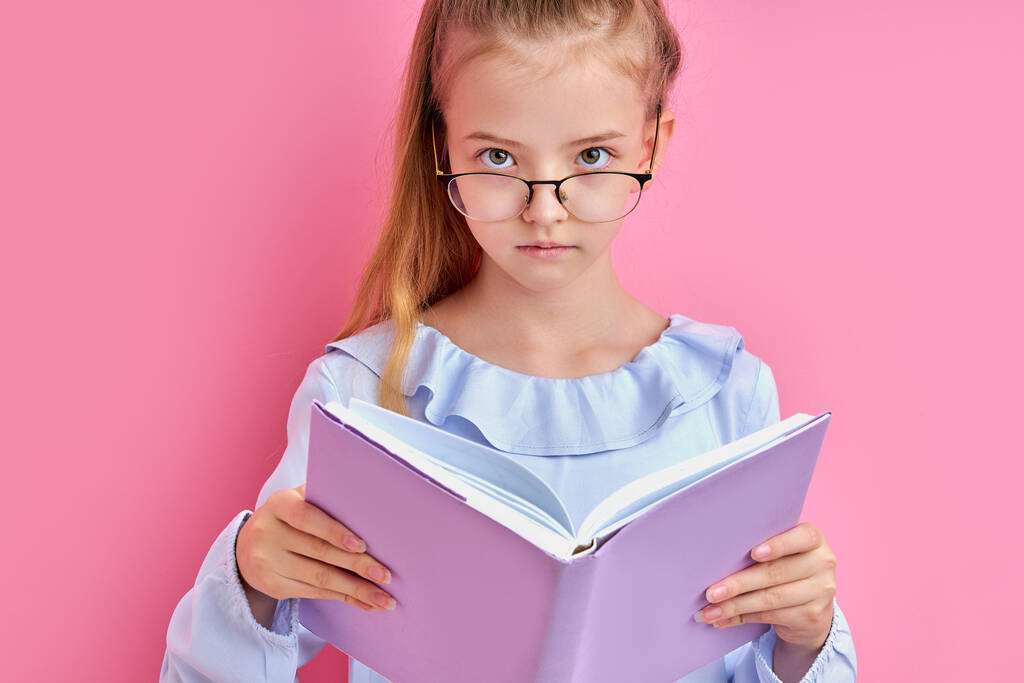 Αξιολάτρευτο καυκάσιο κορίτσι με γυαλιά διαβάστε ένα βιβλίο απομονωμένο - Φωτογραφία, εικόνα