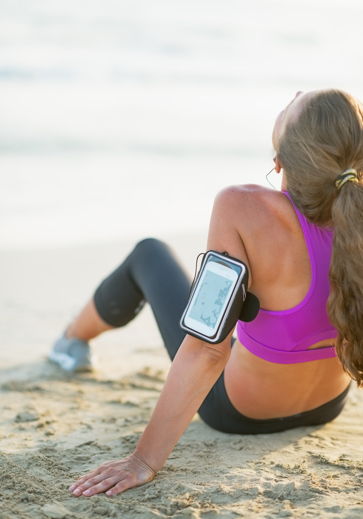 Fitness junge Frau sitzt am Strand. Rückansicht - Foto, Bild