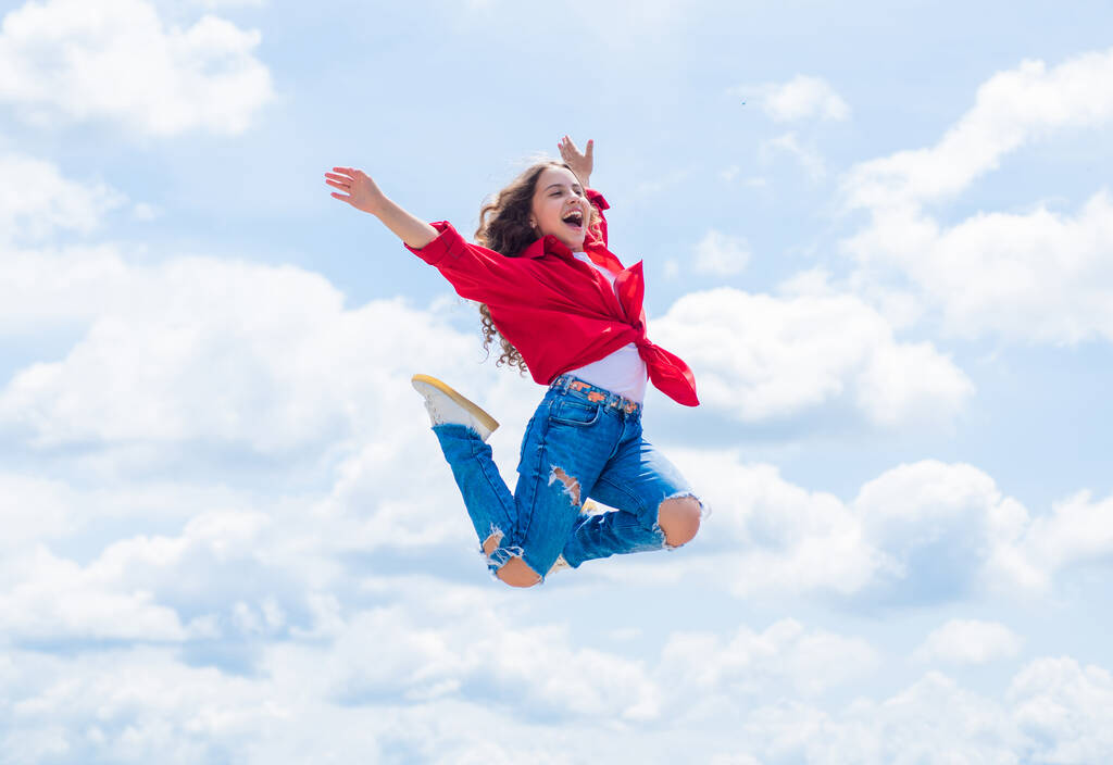 Улыбающийся ребенок прыгает так высоко. беззаботный и радостный. Детская мода. девушка-подросток на фоне неба на открытом воздухе. Хипстерский прыжок. Счастливого дня детей. Счастливого детства. Уверенная и стильная красота - Фото, изображение