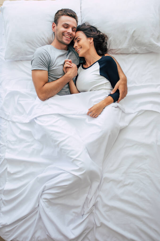 Schlafenszeit. Die Familie schläft. Schöne junge verliebte Paare liegen auf dem großen weißen Bett und ruhen sich aus. Mann und Frau zusammen im Bett. Foto von oben - Foto, Bild
