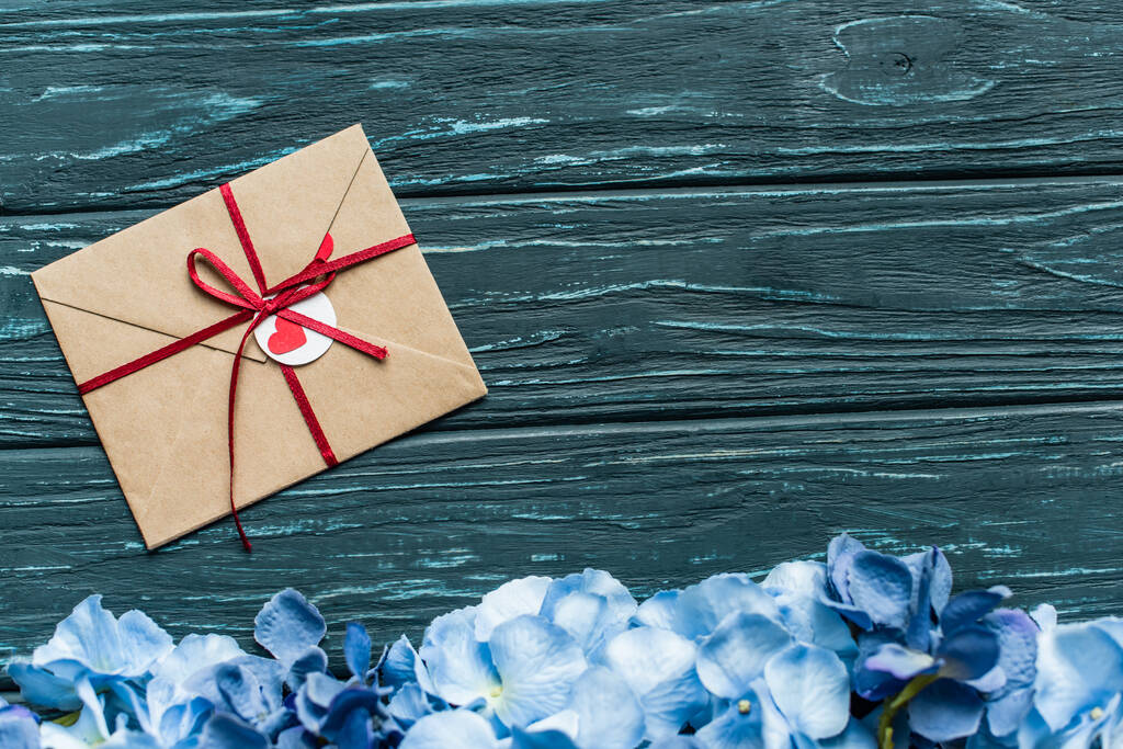 vista superior de fundo verde de madeira com borda floral azul e envelope - Foto, Imagem