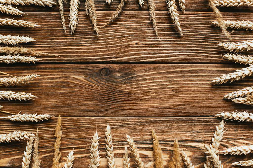 vista superior del marco de las espigas de trigo sobre fondo de madera - Foto, Imagen