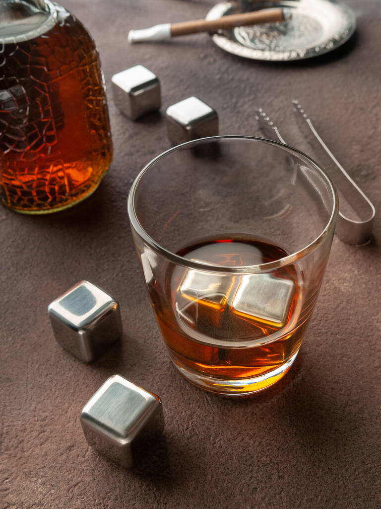 Cubes en acier imitant la glace. Pour rafraîchir les boissons. Avec un verre de whisky. Sur fond brun. Vue d'en haut. - Photo, image