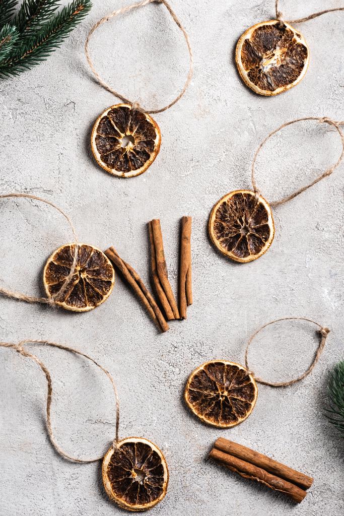 Top view of dried orange pieces with strings, cinnamon sticks and pine branches  - Photo, Image