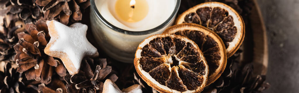 Panoramic shot of scented candle with cookie and pine cones - Photo, Image
