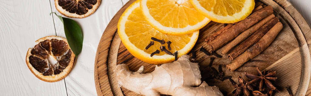 Foto panorámica de plato de madera con especias y rodajas de naranja fresca - Foto, imagen