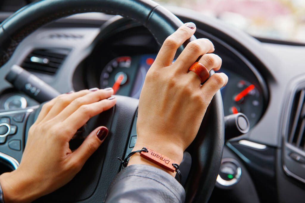 Conceito de tiro: as mãos da menina no volante de um carro, uma pulseira com o sonho de inscrição na mão. - Foto, Imagem