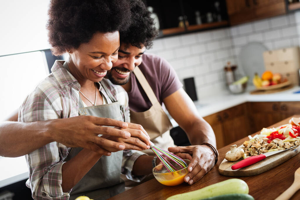 キッチンで健康的な食べ物を準備する幸せなアフリカのカップル - 写真・画像