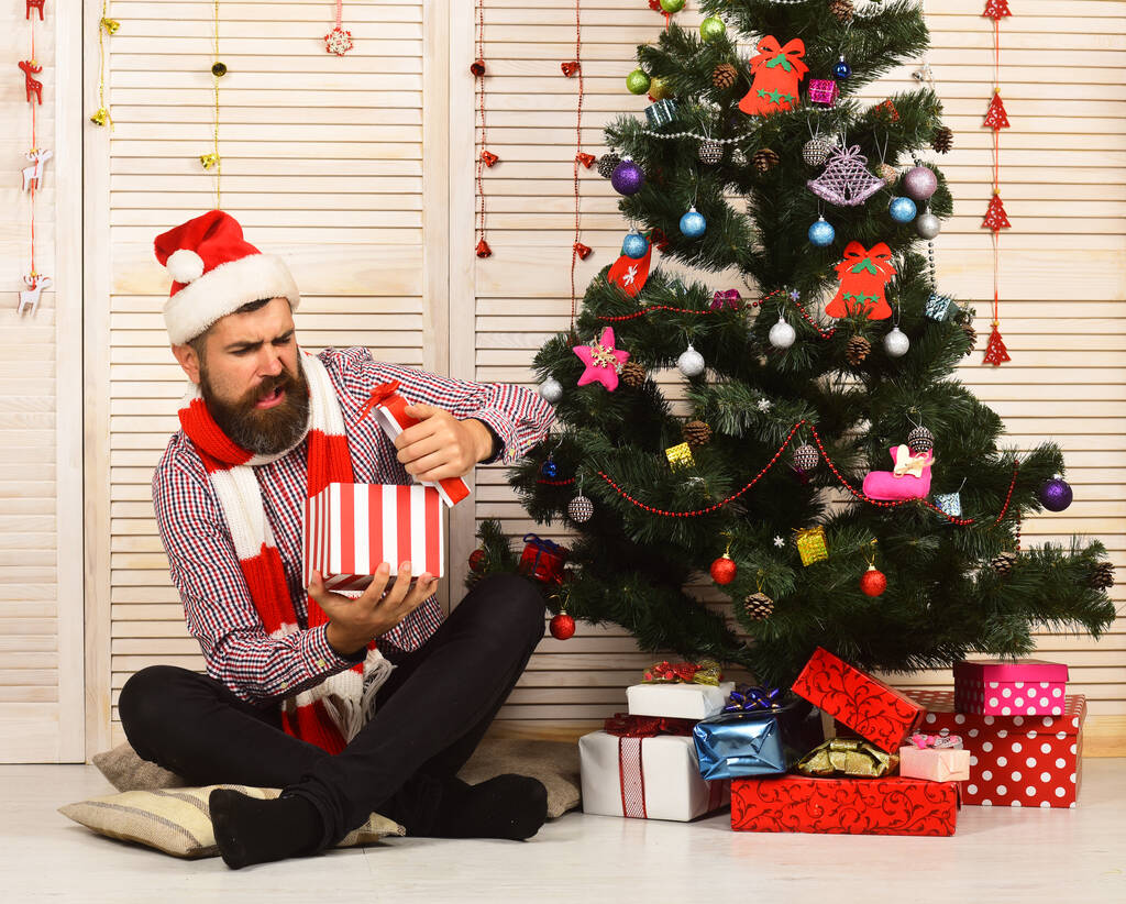 Санта-Клаус с разочарованным лицом на фоне красных гирлянд - Фото, изображение