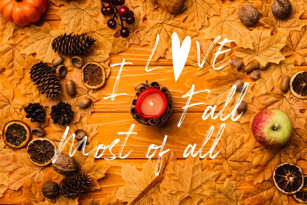 top view of burning candle with autumnal decoration near i love fall most of all lettering on wooden background - Photo, Image