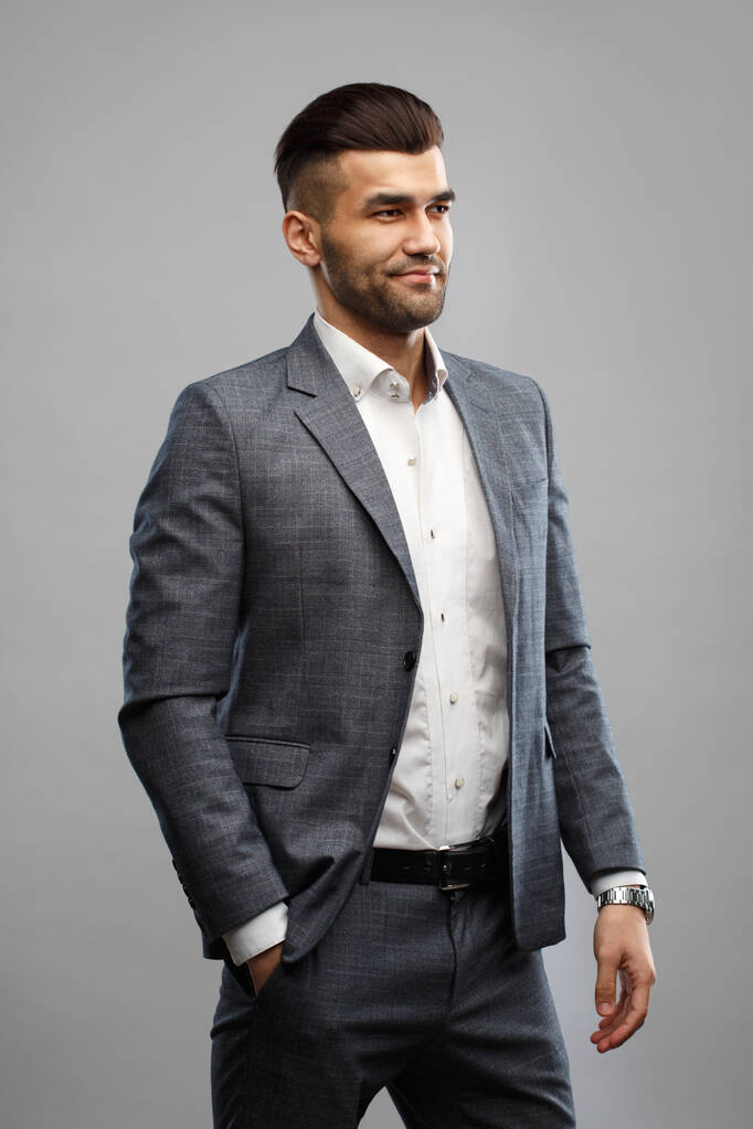 Молодий стильний чоловік в елегантному костюмі ізольований на сірому фоні
. - Фото, зображення