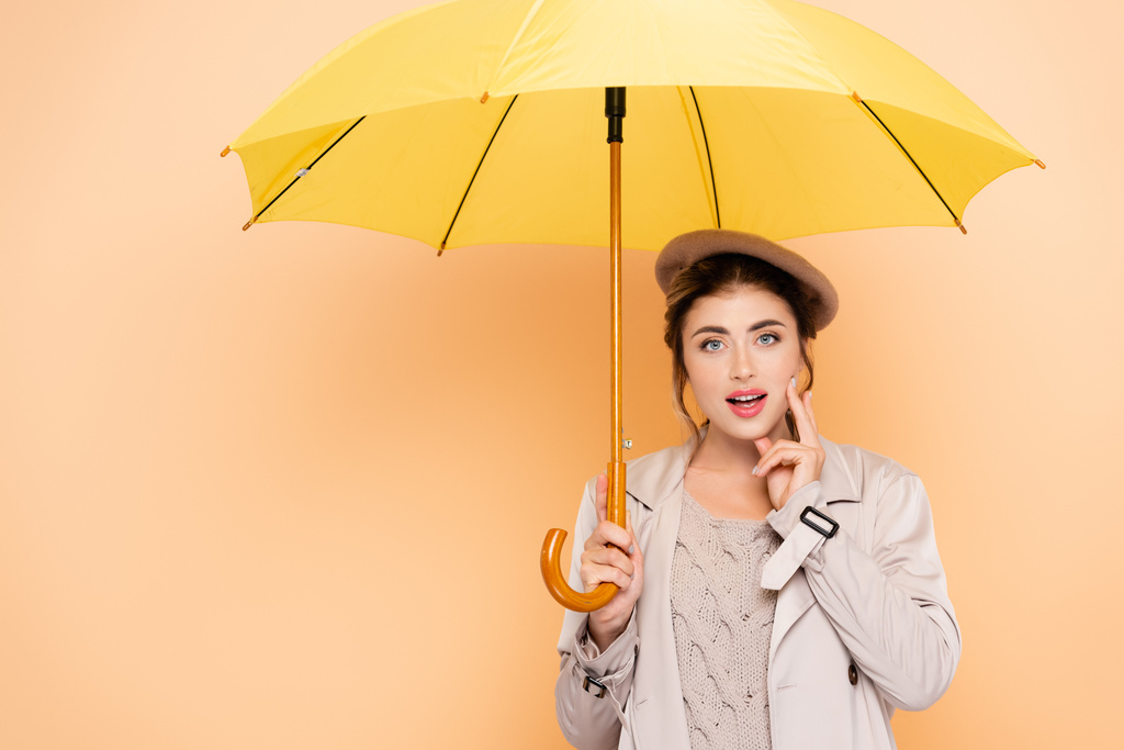tyylikäs nainen syksyllä asu koskettaa kasvot keltainen sateenvarjo persikka - Valokuva, kuva
