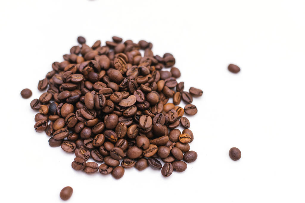 A kávébabok fehér alapon szóródnak szét. A kávé textúrája. - Fotó, kép