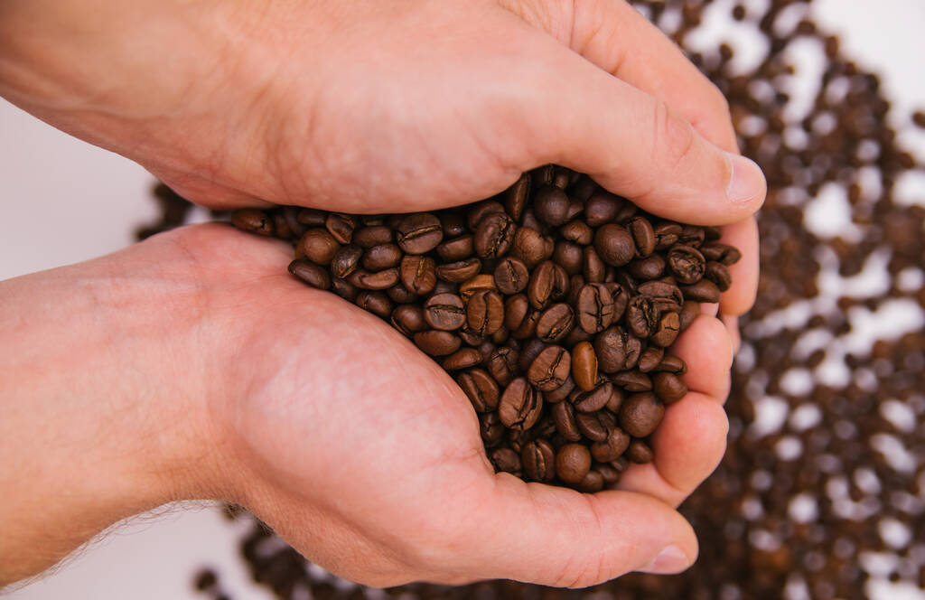 Men's hands hold a handful of coffee beans. Roasted coffee beans. Background. - Photo, Image