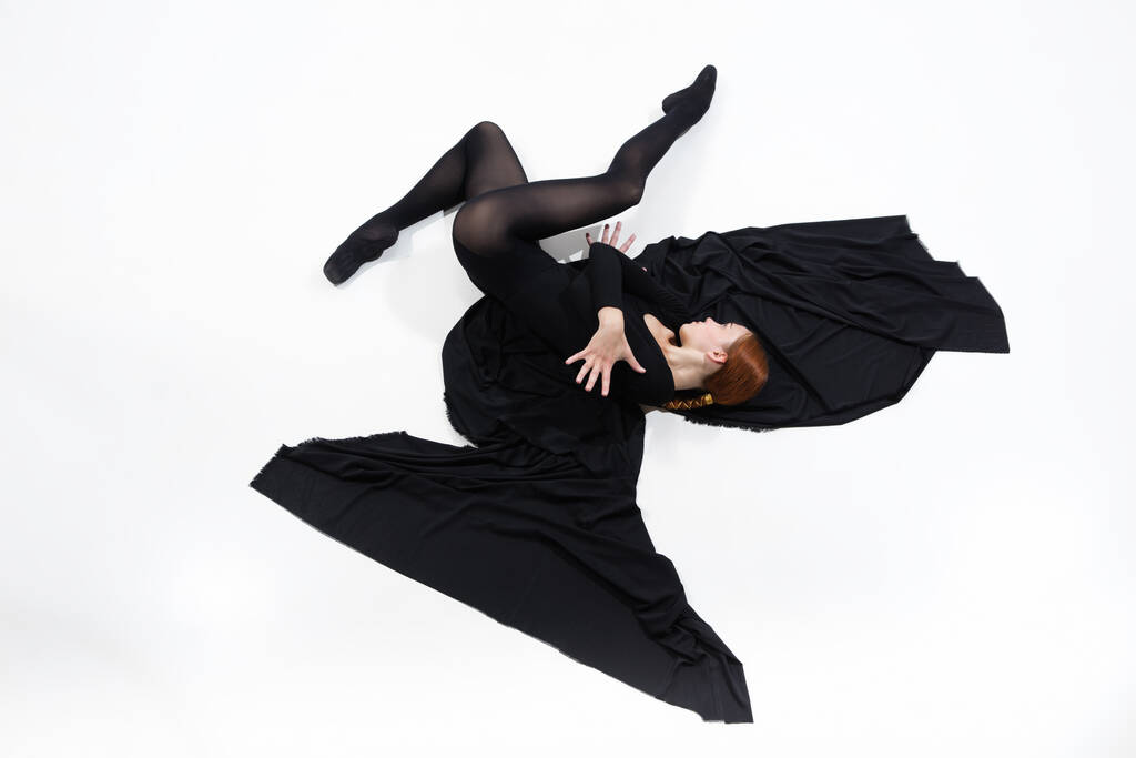 Joven y elegante bailarina de ballet en estilo minimalista negro aislado sobre fondo de estudio blanco - Foto, imagen