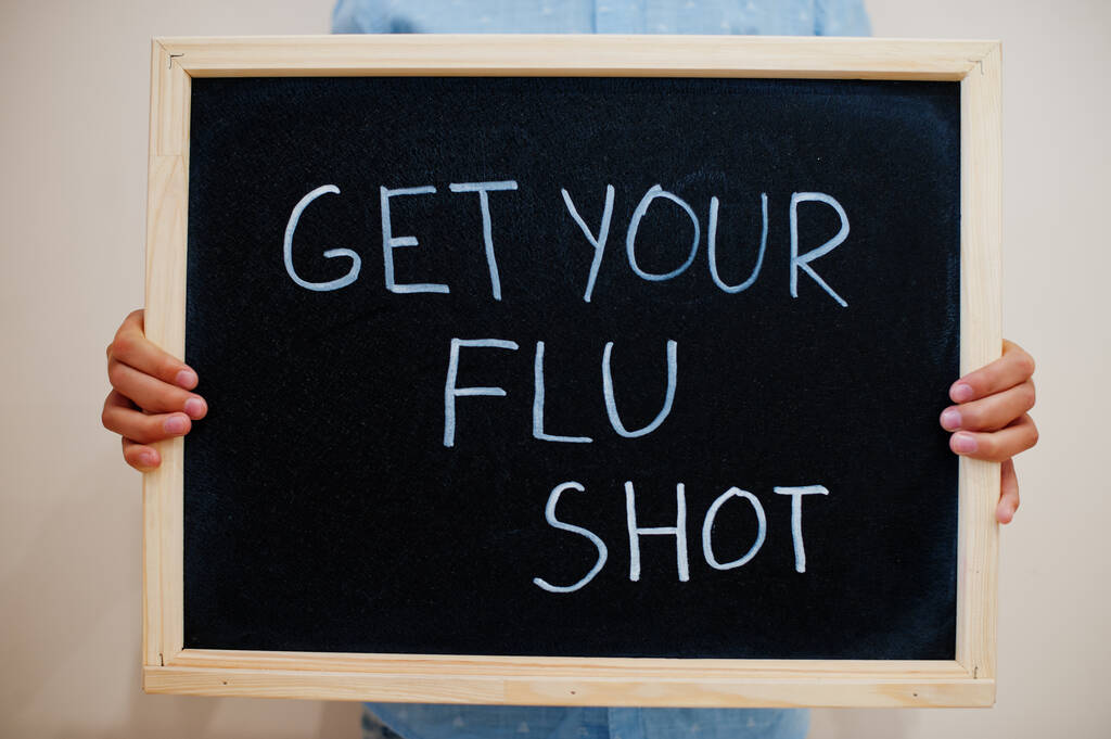 Get your flu shot. Coronavirus concept. Boy hold inscription on the board. - Photo, Image