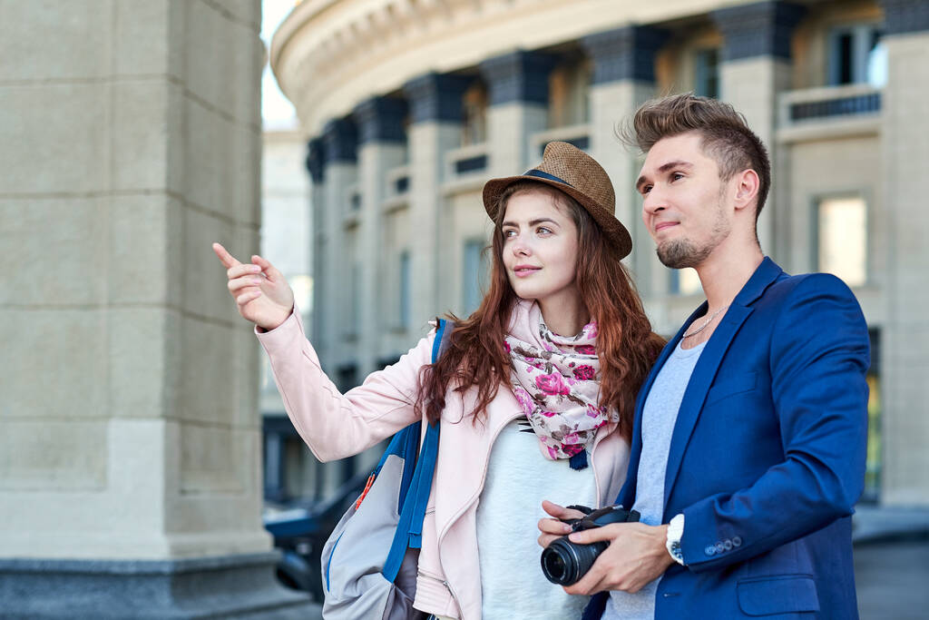 Счастливая влюбленная пара туристов, фотографирующихся на экскурсии или во время экскурсии по городу. Фото на фоне городской архитектуры - Фото, изображение