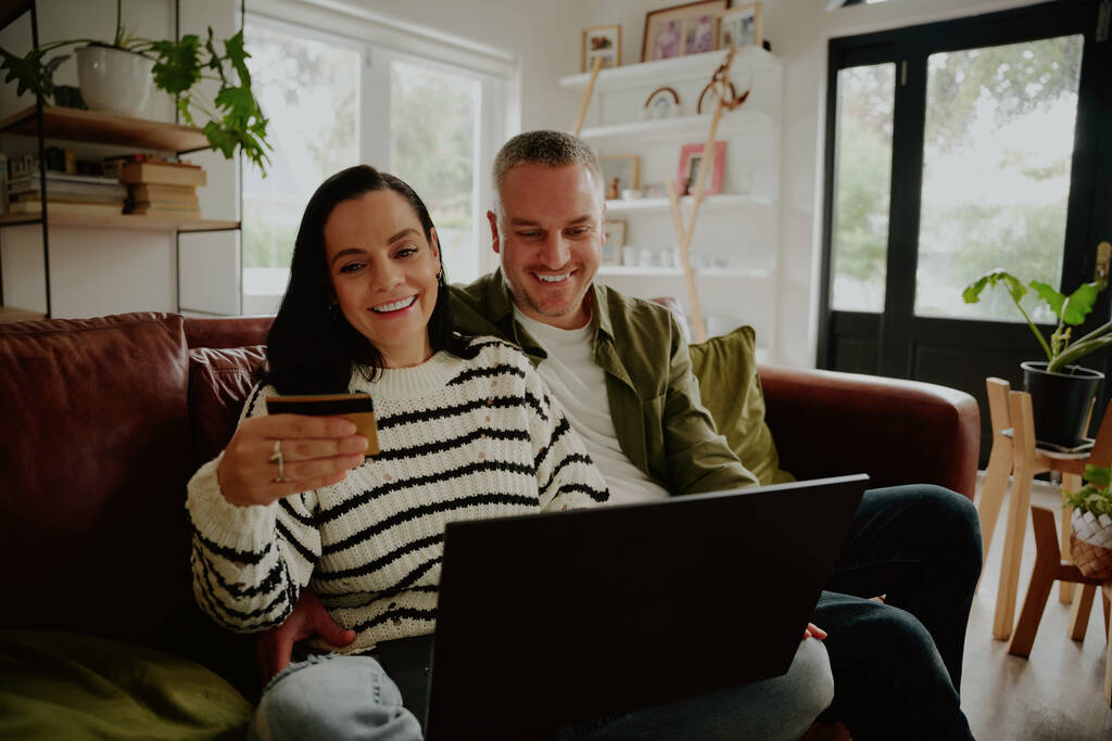 Usmívající se pár pomocí debetní karty, aby on-line nákupní transakce doma - Fotografie, Obrázek