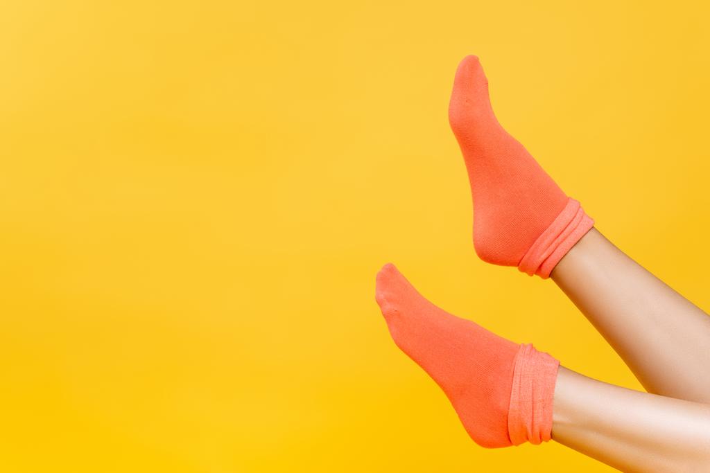 黄色に隔離された柔らかいオレンジの靴下の女性の足の作物ビュー  - 写真・画像