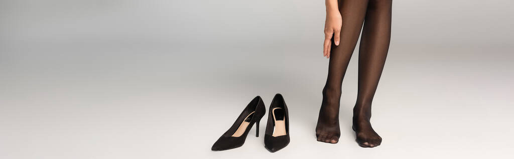 灰色の背景に黒い靴の近くに立って暗いタイツの女性、バナー - 写真・画像