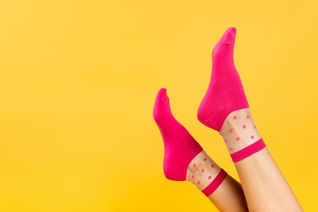 Προβολή των θηλυκών ποδιών σε ροζ κάλτσες που απομονώνονται σε κίτρινες  - Φωτογραφία, εικόνα