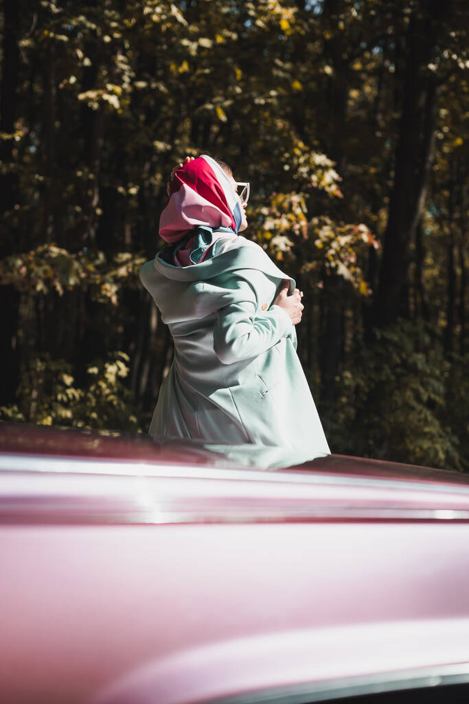 Vissza kilátás elegáns nő napszemüvegben megható kabát közelében autó szabadban  - Fotó, kép