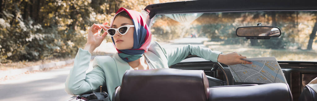 Женщина с картой касающихся солнцезащитных очков в машине без крыши на размытом переднем плане, баннер - Фото, изображение