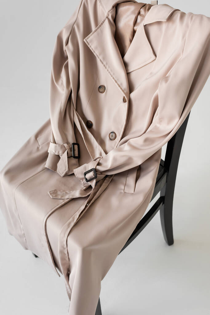 stijlvolle trench jas op stoel en witte achtergrond - Foto, afbeelding