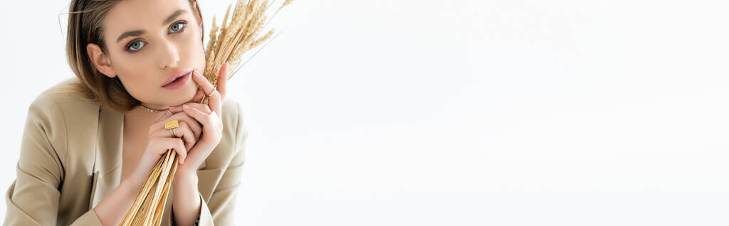 junge Frau blickt in die Kamera und hält Weizen auf weiß, Banner - Foto, Bild