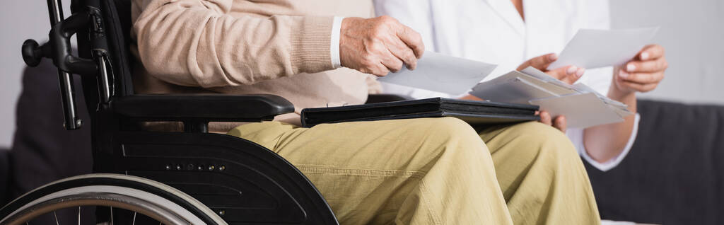 vista recortada del hombre discapacitado mirando fotos con el trabajador social, pancarta - Foto, Imagen