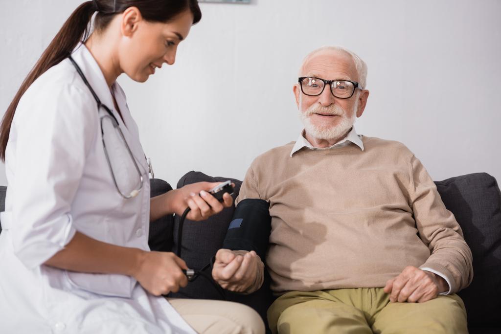 collage de enfermera geriátrica examinando hombre anciano con tonómetro en casa - Foto, Imagen
