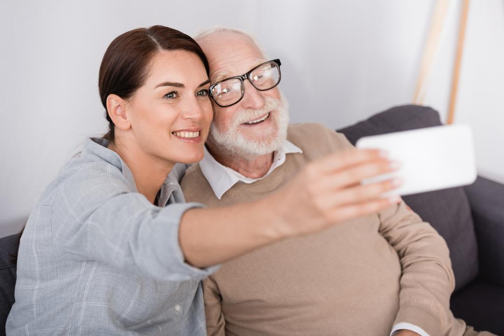 mujer feliz y hombre mayor tomando selfie en el teléfono móvil en primer plano borrosa - Foto, Imagen