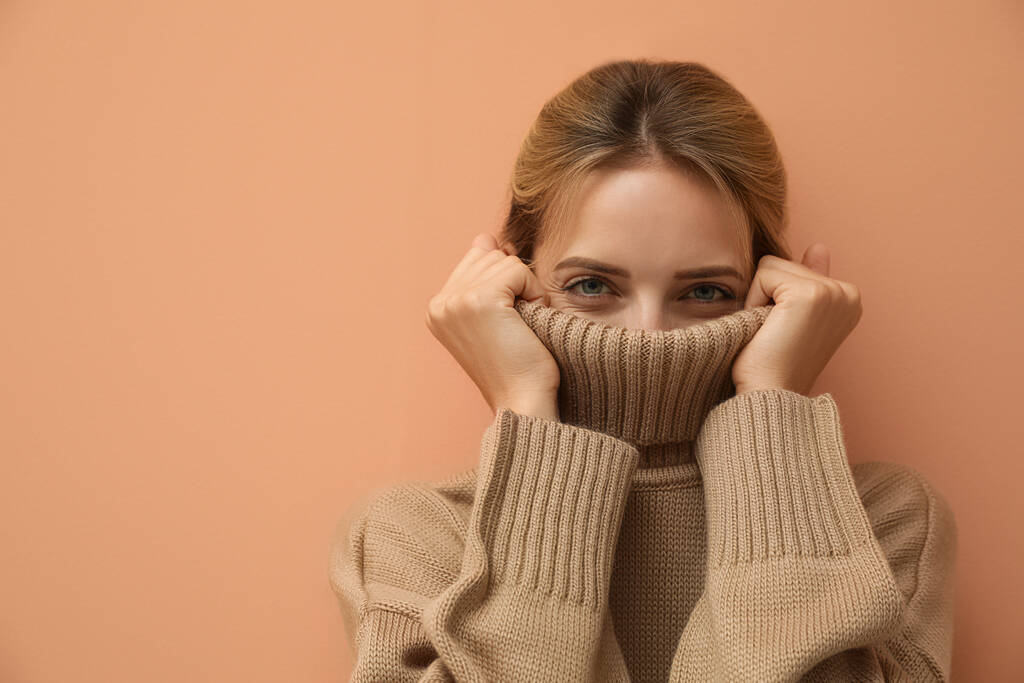 Gyönyörű fiatal nő kötött pulóvert visel világosbarna háttérrel. A szöveg helye - Fotó, kép